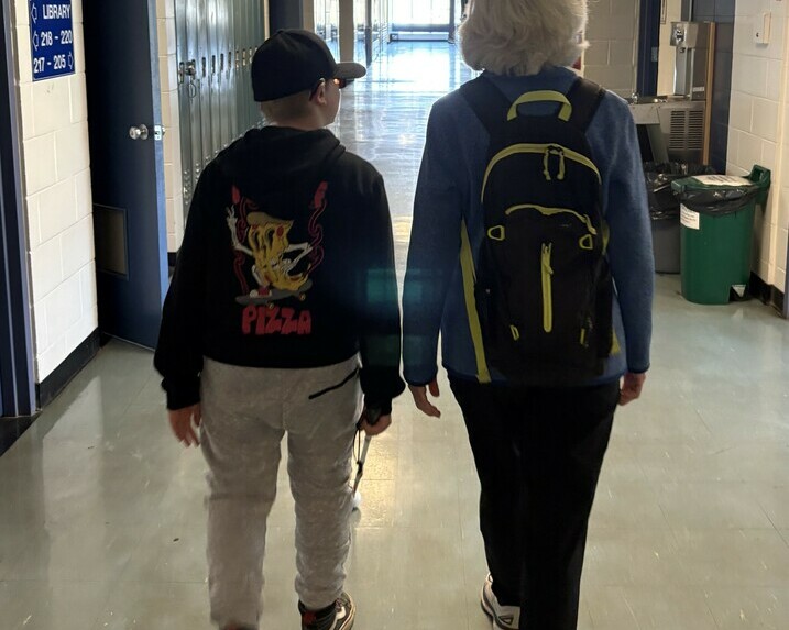 Student and O&M specialist are walking beside one another while student uses the long cane