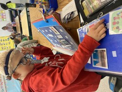 A student moving photos and clip art images between a calendar strip on a slant board and a storage binder