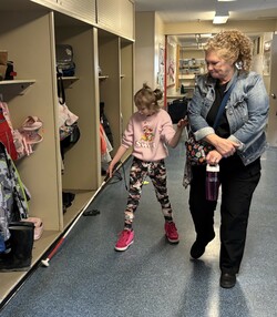 Intervenor watches as student uses her long cane in constant contact technique to walk down the hallway